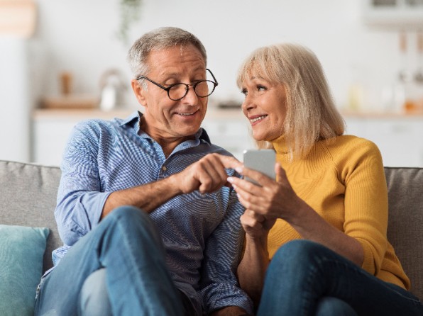 En man och en kvinna med en mobil i en soffa. Foto: Adobe Stock.