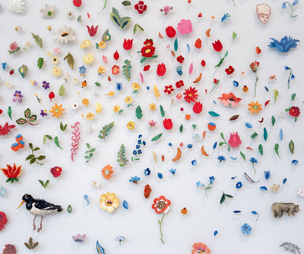 Konstverk. Broderade färggranna figurer som blommor, fåglar med mera. Det stora minnet. Foto Simon Fagéus