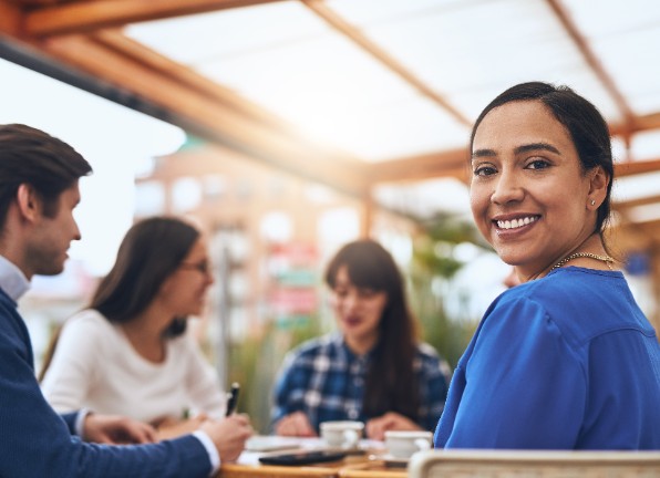 Några kvinnor och en man pratar vid ett bord. Foto: Adobe Stock